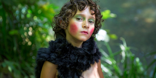 Child in wearing fur outfit and face paint in forest