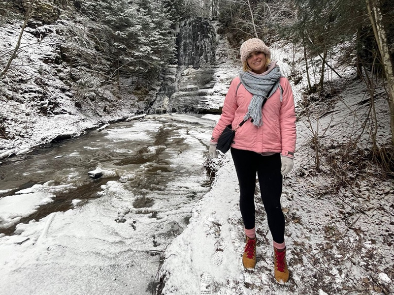 Erica Capcechi in snowy forest by a river in Kakabeka Falls Natural Park.