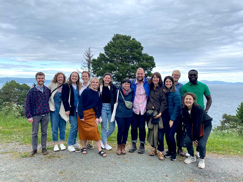 Group of smiling postgraduate students on forested clifftop in Norway