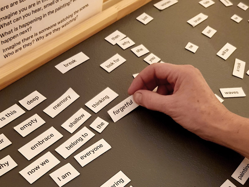 Hand selecting the word 'forgetful' from a collection of magnetic words
